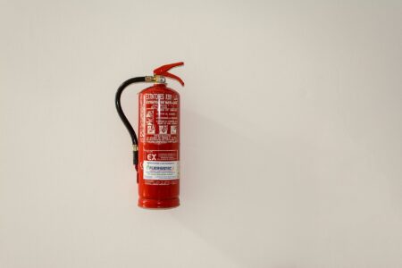Onde Comprar Extintores de Incêndio? Guia Para Fazer a Escolha Certa e Comprar com Segurança Extintor de incêndio vermelho fixado em uma parede clara.