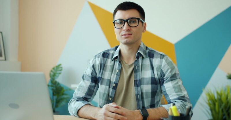 Empreendedor paraense cria holding de marketing e tecnologia com meta de R$ 50 milhões até 2030 Um jovem homem com camisa xadrez sentado em uma mesa, sorrindo.